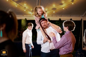 A WPJA wedding photo: A wedding guest dad with daughter on shoulders, enthusiastically celebrates at the end of the night in Sunken Gardens St. Petersburg, Florida.